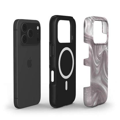 Black smartphone next to a sleek black magnetic case and a dreamy rose patterned protective cover with pink, gray, and silver swirls, trendy and feminine style.