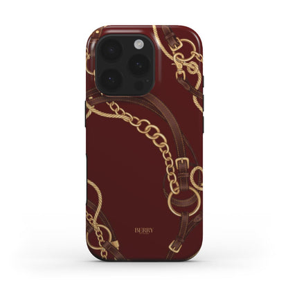 Trendy burgundy phone case with elegant gold chain and brown equestrian strap design, combining feminine and popular aesthetic for a beautiful look.