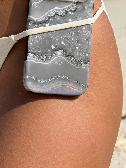 Trendy phone case with silver, gray, and multicolored marble quartz design resting on tanned skin, exuding feminine and aesthetic summer vibes.